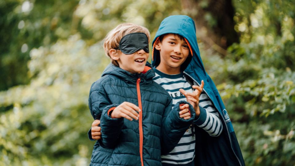 Enfants jouant dans la forêt avec les yeux masqués.